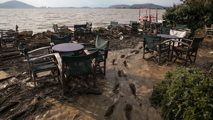 Locals try to move water and mud from a tavern following a storm at the village of Politika, on Evia island, northeast of Athens, on Sunday, Aug. 9, 2020. Five people have been found dead and dozens have been trapped in their homes and cars from a storm that has hit the island of Evia, in central Greece, police say. (AP Photo/Yorgos Karahalis)