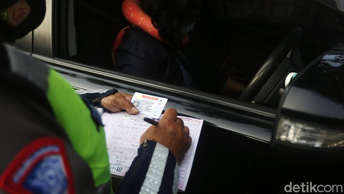 Petugas Polisi Lalu Lintas (Polantas) Satlantas Polres Jakarta Timur saat melakukan penilangan pada pengendara mobil yang melanggar aturan Ganjil-Genap di Simpang Cawang, Jakarta Timur, Senin (10/8/2020). Sanksi tilang bagi pelanggar pembatasan kendaraan bermotor berdasarkan nomor polisi ganjil dan genap diberlakukan lagi di Jakarta mulai hari ini. Pembatasan itu sebelumnya dicabut sementara sejak pertengahan Maret lalu karena adanya pandemi Covid-19 yang berujung pada penerapan pembatasan sosial berskala besar (PSBB).