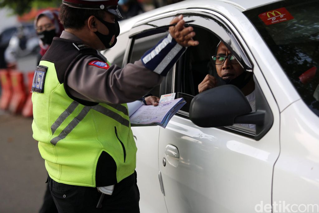 Petugas Polisi Lalu Lintas (Polantas) Satlantas Polres Jakarta Timur saat melakukan penilangan pada pengendara mobil yang melanggar aturan Ganjil-Genap di Simpang Cawang, Jakarta Timur, Senin (10/8/2020). Sanksi tilang bagi pelanggar pembatasan kendaraan bermotor berdasarkan nomor polisi ganjil dan genap diberlakukan lagi di Jakarta mulai hari ini. Pembatasan itu sebelumnya dicabut sementara sejak pertengahan Maret lalu karena adanya pandemi Covid-19 yang berujung pada penerapan pembatasan sosial berskala besar (PSBB).