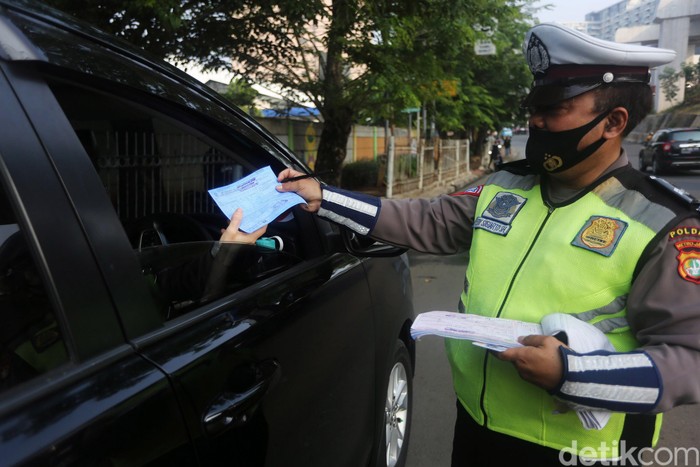 Petugas Polisi Lalu Lintas (Polantas) Satlantas Polres Jakarta Timur saat melakukan penilangan pada pengendara mobil yang melanggar aturan Ganjil-Genap di Simpang Cawang, Jakarta Timur, Senin (10/8/2020). Sanksi tilang bagi pelanggar pembatasan kendaraan bermotor berdasarkan nomor polisi ganjil dan genap diberlakukan lagi di Jakarta mulai hari ini. Pembatasan itu sebelumnya dicabut sementara sejak pertengahan Maret lalu karena adanya pandemi Covid-19 yang berujung pada penerapan pembatasan sosial berskala besar (PSBB).