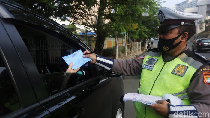 Petugas Polisi Lalu Lintas (Polantas) Satlantas Polres Jakarta Timur saat melakukan penilangan pada pengendara mobil yang melanggar aturan Ganjil-Genap di Simpang Cawang, Jakarta Timur, Senin (10/8/2020). Sanksi tilang bagi pelanggar pembatasan kendaraan bermotor berdasarkan nomor polisi ganjil dan genap diberlakukan lagi di Jakarta mulai hari ini. Pembatasan itu sebelumnya dicabut sementara sejak pertengahan Maret lalu karena adanya pandemi Covid-19 yang berujung pada penerapan pembatasan sosial berskala besar (PSBB).