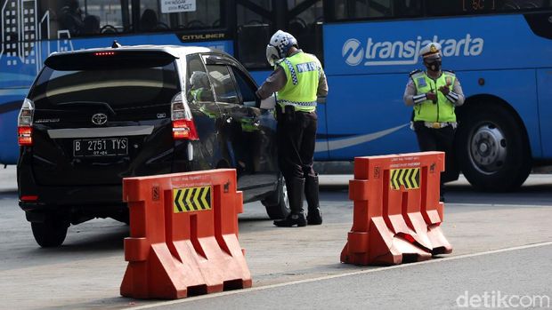 Petugas Polisi Lalu Lintas (Polantas) Satlantas Polres Jakarta Timur saat melakukan penilangan pada pengendara mobil yang melanggar aturan Ganjil-Genap di Simpang Cawang, Jakarta Timur, Senin (10/8/2020). Sanksi tilang bagi pelanggar pembatasan kendaraan bermotor berdasarkan nomor polisi ganjil dan genap diberlakukan lagi di Jakarta mulai hari ini. Pembatasan itu sebelumnya dicabut sementara sejak pertengahan Maret lalu karena adanya pandemi Covid-19 yang berujung pada penerapan pembatasan sosial berskala besar (PSBB).