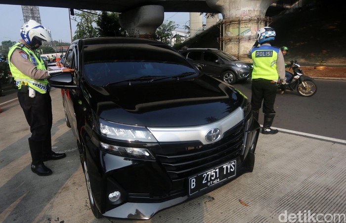Petugas Polisi Lalu Lintas (Polantas) Satlantas Polres Jakarta Timur saat melakukan penilangan pada pengendara mobil yang melanggar aturan Ganjil-Genap di Simpang Cawang, Jakarta Timur, Senin (10/8/2020). Sanksi tilang bagi pelanggar pembatasan kendaraan bermotor berdasarkan nomor polisi ganjil dan genap diberlakukan lagi di Jakarta mulai hari ini. Pembatasan itu sebelumnya dicabut sementara sejak pertengahan Maret lalu karena adanya pandemi Covid-19 yang berujung pada penerapan pembatasan sosial berskala besar (PSBB).