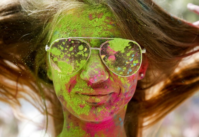 A woman blows colored powder from her hands during the Holi Festival in a city park in Kyiv, Ukraine, Saturday, Aug. 8, 2020. Ukrainians mark a popular ancient Hindu Holi Festival, also known as the festival of colors, or the festival of love, which signifies the victory of good over evil. Normally celebrated in spring, but postponed due to the coronavirus. (AP Photo/Efrem Lukatsky)