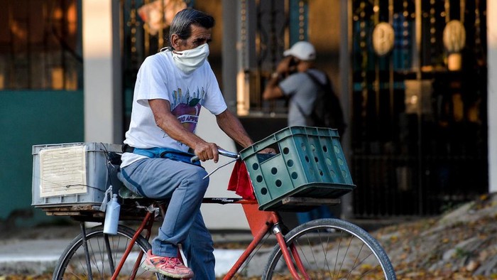 A man wearing a face mask rides on his bicycle along a street of Havana, on July 29, 2020. - Cuba has 2588 confirmed cases of COVID-19 and 87 deceased. (Photo by YAMIL LAGE / AFP)