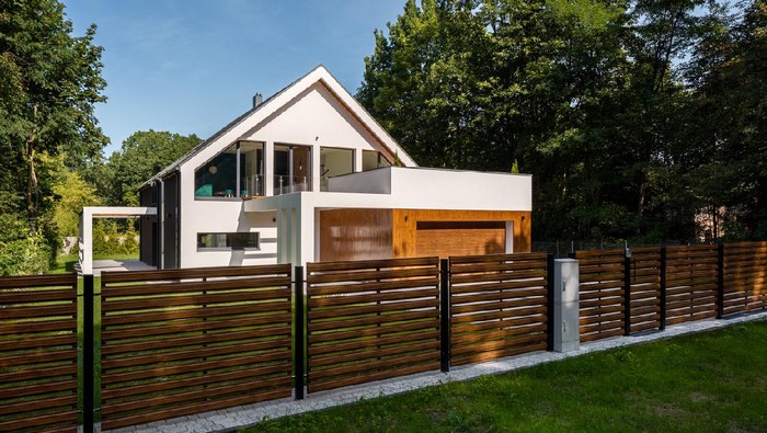 Spacious white house with wooden decoration on garage and wood style fence