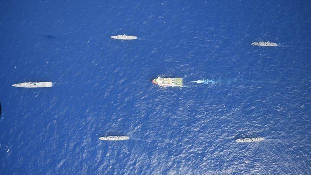 In this photo provided by the Turkish Defense Ministry, Turkey's research vessel, Oruc Reis, in red and white, is surrounded by Turkish navy vessels as it was heading in the west of Antalya on the Mediterranean, Turkey, Monday, Aug 10, 2020. Tension remains high between Greece and Turkey, whose warships are in the eastern Mediterranean where Turkey has sent a research vessel to carry out seismic research for energy resources in an area Greece says is on its continental shelf. (Turkish Defense Ministry via AP, Pool)