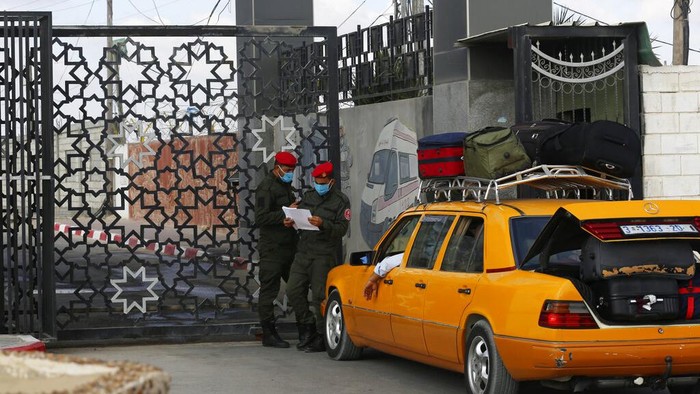 Passengers sit next to their luggage as they wait to cross the border to the Egyptian side of Rafah crossing, in Rafah, Gaza Strip, Tuesday, Aug. 11, 2020. Egypt reopened Rafah Crossing for three days starting Tuesday for humanitarian cases in and out of the Gaza Strip, including medical patients and people who had Egyptian and international citizenship. The border was closed since March. (AP Photo/Adel Hana)