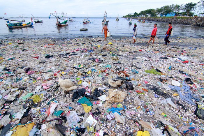 Nelayan berjalan di antara tumpukan sampah di Pelabuhan Muncar, Banyuwangi, Jawa Timur, Selasa (11/8/2020). Menurut warga sekitar, sampah yang menumpuk di sepanjang pantai akibat banjir besar pada tahun 2014 itu, juga diperparah oleh kebiasaan warga yang membuang sampah di tempat itu. ANTARA FOTO/Budi Candra Setya/hp.