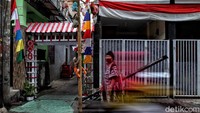 Seorang warga beraktivitas di dekat gapura yang dihiasi dengan warna merah dan putih dalam rangka menyambut HUT RI ke-75.