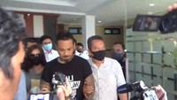 Terlihat tangannya diikat cable ties saat dibawa penyidik Polda Bali. Jerinx juga terlihat mengenakan kaus Bali Tolak Rapid. Seperti kedatangan sebelumnya, hari ini Jerinx juga tidak memakai masker. (dok Istimewa)