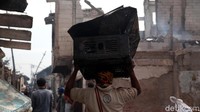 Warga mengevakuasi barang-barang yang masih bisa dipergunakan dari puing-puing kebakaran.