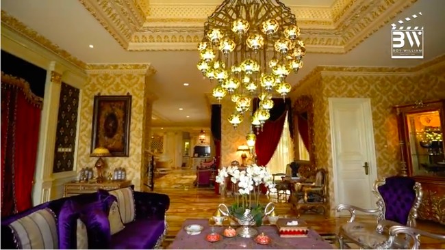 Ruang tamu dihiasi lampu gantung besar dan bantal-bantal beraksen ungu sehingga tak terasa monoton. (Foto: YouTube/Boy William)