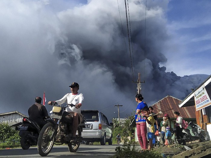 Pengendara melintas di Jalan Karo-Langkat dengan latar belakang Gunung Sinabung yang menyemburkan material vulkanik di Desa Kutarayat, Naman Teran, Karo, Sumatera Utara, Kamis (13/8/2020). Pusat Vulkanologi dan Mitigasi Bencana Geologi (PVMBG) menyatakan Gunung Sinabung berstatus level III atau siaga dan meminta masyarakat untuk tidak melakukan aktivitas di desa yang telah direlokasi. ANTARA FOTO/Sastrawan Ginting/Lmo/wsj.