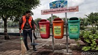 Mereka menyapu sampah dengan memakai rompi bertuliskan Pelanggar PSBB.