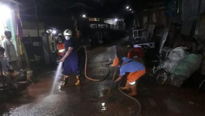 Personel pemadam kebakaran membersihkan endapan lumpur luapan kali di jalan umum Kelurahan Kalisari, Pasar Rebo, Jakarta Timur, Kamis (13/8/2020) malam. (ANTARA/HO-Damkar Jaktim).
