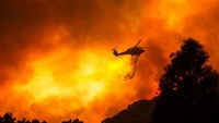 Helikopter berusaha melakukan pemadaman pada area yang terbakar dengan bom air.