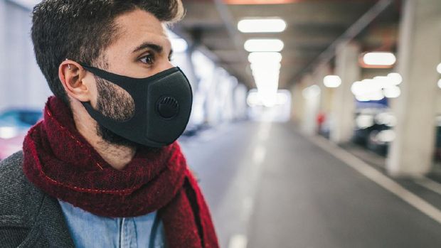 1211618952 masker respirator Side view image of young man wearing anti-smog mask for health and lungs protection in the city. City pollution concept