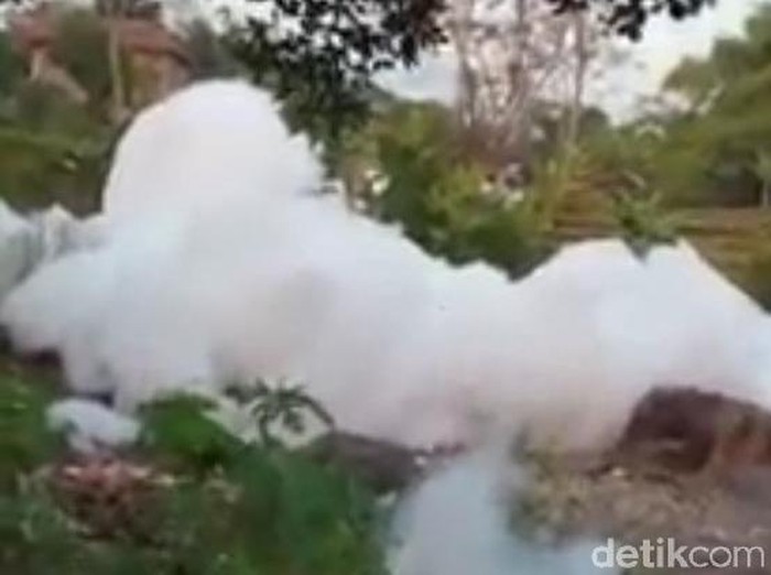 Busa bak awan meluap dari saluran air hingga menutup jalan kampung di Kecamatan Gempol, Kabupaten Pasuruan. Sementara saluran air yang tertutup gunungan busa itu mencapai 500 meter.