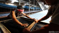 Dua orang pekerja tampak mengenakan face shield atau pelindung wajah saat tengah menyelesaikan pembuatan seragam sekolah industri rumahan batik printing di Siwal, Sukoharjo, Jawa Tengah.
