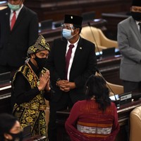 Orang nomor satu di Indonesia ini lalu menyempurnakan gayanya dengan sebuah sabuk emas dan kalung senada. Tidak ketinggalan sebuah ikat kepala yang meruncing ke atas. Mengedepankan protokol kesehatan, Jokowi tetap memakai masker berwarna hitam sehingga tetap senada dengan busananya. (Foto: ANTARA FOTO/AKBAR NUGROHO GUMAY)