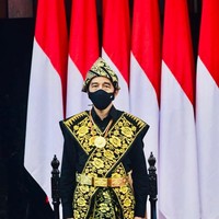 Busana pilihan Jokowi tersebut terdiri dari kemeja dan celana panjang serba hitam yang dibungkus selendang tenun motif bunga bernuansa keemasan secara menyilang pada bagian dada. Tidak ketinggalan sebuah sarung senada yang dililitkan sebagai bawahan. (Foto: Biro Pers Sekretariat Presiden)