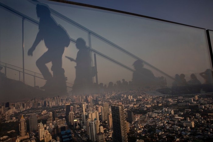 Tujuan Liburan Teraman di Dunia BANGKOK - JANUARY 14 : Tourists walk uptown get a better view at the Bangkok skyline from the 78-floor mirrored skyscraper viewing deck King Power Mahanakhon tower in Bangkok, Thailand on January 14, 2020. Thick, unhealthy smog continues to plague much Bangkok and the North, with the worst pollution in Lampang province near Chiang Mai. According to the Pollution Control Dept unsafe levels of particulate matter 2.5 micrometres and less in diameter (PM2.5) at 11 of the 15 air quality measurement stations it operates in the North. (Photo by Paula Bronstein/Getty Images )