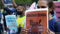 Massa membawa atribut aksi seperti spanduk dan poster.