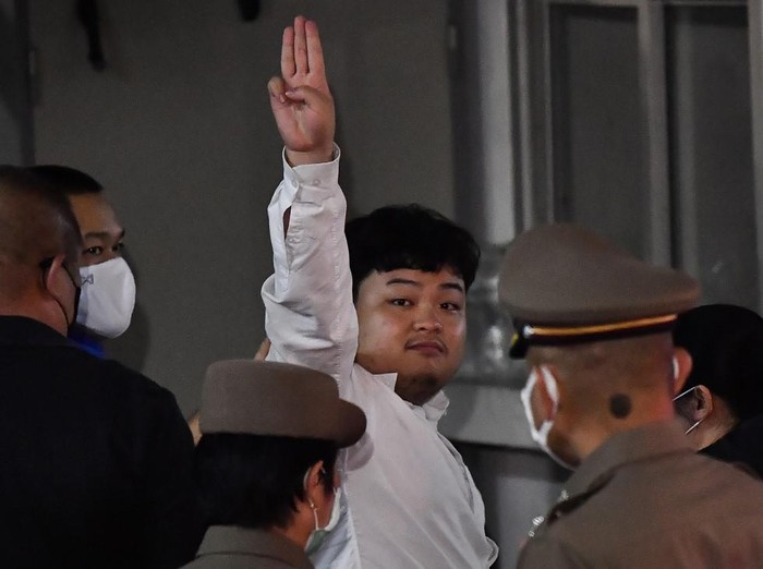 Thai pro-democracy activist Parit Chiwarak makes a salute as police escort him on arrival at Samanrat police station in Bangkok on August 14, 2020. - Thai police on August 14 arrested prominent democracy activist, Parit Chiwarak also known as 