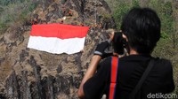 Seorang warga mengabadikan proses pengibaran bendera merah putih di puncak bukit Sepikul. Bram Selo/detikcom.