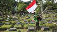Saat tengah memotong rumput di kawasan TPU Karet Bivak,  para petugas tampak membawa bendera Merah Putih.  