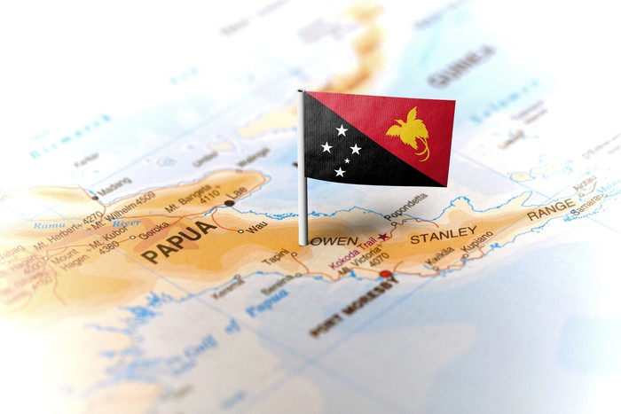 The flag of Papua New Guinea pinned on the map. Horizontal orientation. Macro photography.