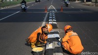 Pengecatan pembatas jalan itu tampak dilakukan oleh sejumlah petugas pasukan oranye.
