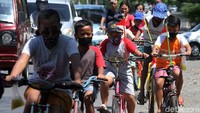 Beberapa anak menggunakan sepeda dan bendera plastik melintasi jalanan di Pucang Sawit, Surakarta, Jawa Tengah, Senin (17/8/2020).