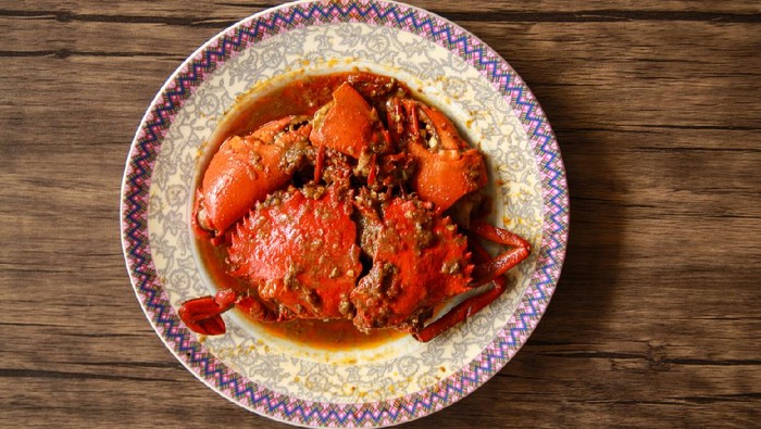 Kepiting saos Padang Crab in Padang sauce or Padang crab (Indonesian: Kepiting saus Padang) on wood background.