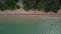 Foto udara para pemuda membentangkan bendera merah putih di Pantai Toronipa, Konawe, Sulawesi Tenggara, Senin (17/8/2020).