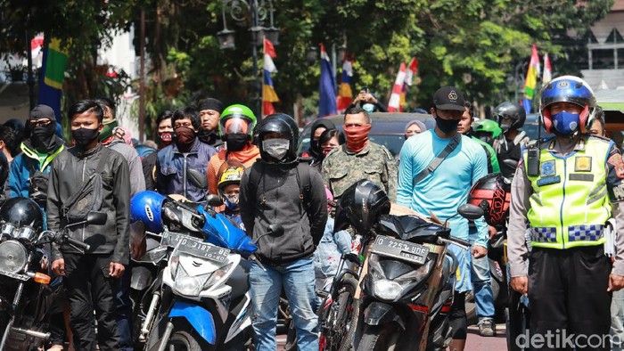 Para pengendara berhenti sejenak untuk mendengarkan lagu Indonesia Raya.