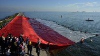 Sejumlah mahasiswa pecinta alam 45 dan warga membentangkan bendera merah putih raksasa di pinggir Pantai Pulau Lae-Lae, Makassar, Sulawesi Selatan, Senin (17/8/2020). Pembentangan bendera merah putih raksasa berukuran 63 x 32 meter oleh mahasiswa pecinta alam 45 dan warga setempat tersebut untuk memeriahkan peringatan HUT ke-75 Kemerdekaan Republik Indonesia. ANTARA FOTO/Abriawan Abhe.
