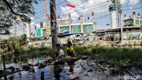Sejumlah anak beraktivitas dengan latar belakang pengibaran bendera Merah Putih di kawasan proyek Jakarta International Stadium, Jakarta Utara, Senin (17/8/2020).