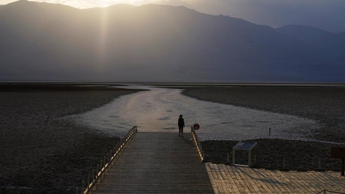 A person walks on a boardwalk at the salt flats at Badwater Basin, Monday, Aug. 17, 2020, in Death Valley National Park, Calif. Death Valley recorded a scorching 130 degrees (54.4 degrees Celsius) Sunday, which if the sensors and other conditions check out, would be the hottest Earth has been in more than 89 years and the third-warmest ever measured. (AP Photo/John Locher)