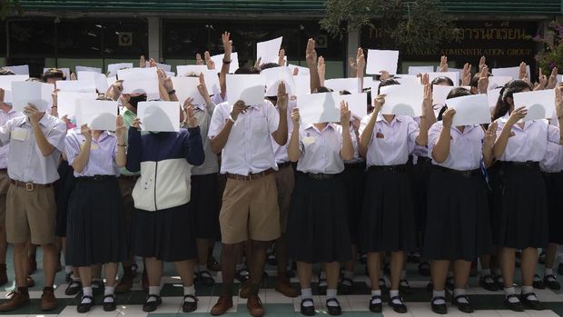 High school students hold up blank sheets of paper and raise their hands with a three-fingered defiance salute at the Samsen Wittayalai school in Bangkok, Thailand on Tuesday, Aug. 18, 2020. A number of students are supporting an anti-government student movement with three core demands: holding new elections, amending the constitution and ending the intimidation of critics of the government. (AP Photo/Sakchai Lalit)