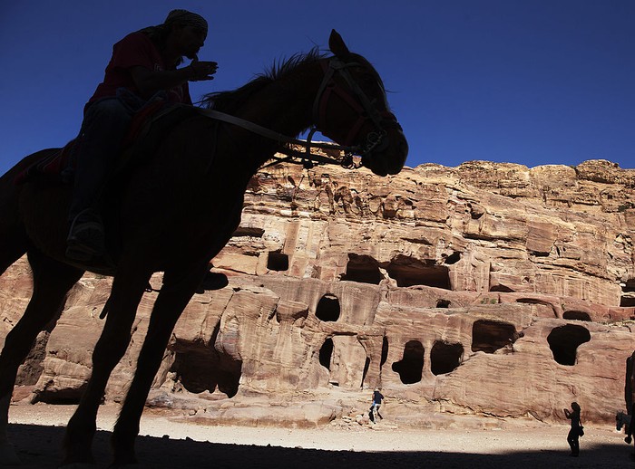 Petra, Yordania PETRA, JORDAN- APRIL 3: Tourists watch a horse pull a carriage as they visit the legendary Petra, Jordan's most famous tourist attraction on April 3, 2015 in Petra, Jordan. Stakeholders have put together an urgent marketing plan to 'salvage' the Kingdom's tourism industry by promoting national tourist products in new and traditional markets worldwide, according to Tourism Minister Nayef Al Fayez. Visits to Jordan and its famous archeological site of Petra have plummeted because of unrest in the broader Middle East, and discounts on airfare and tours to the country have yet to bring visitor numbers back to levels seen in years past. The number of Arab tourists has not been affected by the regional turmoil, but the number of visitors to archaeological sites has recently dropped and those who visit these sites are mostly non-Arabs. (Photo by Jordan Pix/ Getty Iimages)