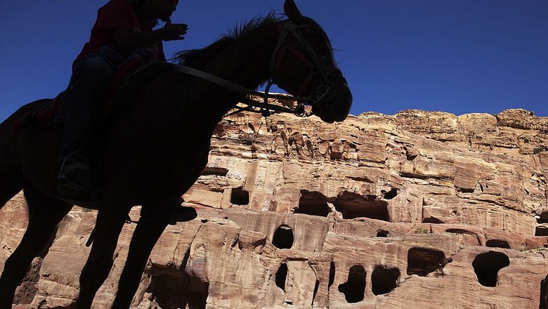 PETRA, JORDAN- APRIL 3: Tourists watch a horse pull a carriage as they visit the legendary Petra, Jordans most famous tourist attraction on April 3, 2015 in Petra, Jordan. Stakeholders have put together an urgent marketing plan to salvage the Kingdoms tourism industry by promoting national tourist products in new and traditional markets worldwide, according to Tourism Minister Nayef Al Fayez. Visits to Jordan and its famous archeological site of Petra have plummeted because of unrest in the broader Middle East, and discounts on airfare and tours to the country have yet to bring visitor numbers back to levels seen in years past. The number of Arab tourists has not been affected by the regional turmoil, but the number of visitors to archaeological sites has recently dropped and those who visit these sites are mostly non-Arabs. (Photo by Jordan Pix/ Getty Iimages)