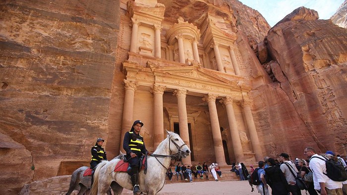 PETRA, JORDAN- APRIL 3: Tourists watch a horse pull a carriage as they visit the legendary Petra, Jordans most famous tourist attraction on April 3, 2015 in Petra, Jordan. Stakeholders have put together an urgent marketing plan to salvage the Kingdoms tourism industry by promoting national tourist products in new and traditional markets worldwide, according to Tourism Minister Nayef Al Fayez. Visits to Jordan and its famous archeological site of Petra have plummeted because of unrest in the broader Middle East, and discounts on airfare and tours to the country have yet to bring visitor numbers back to levels seen in years past. The number of Arab tourists has not been affected by the regional turmoil, but the number of visitors to archaeological sites has recently dropped and those who visit these sites are mostly non-Arabs. (Photo by Jordan Pix/ Getty Iimages)