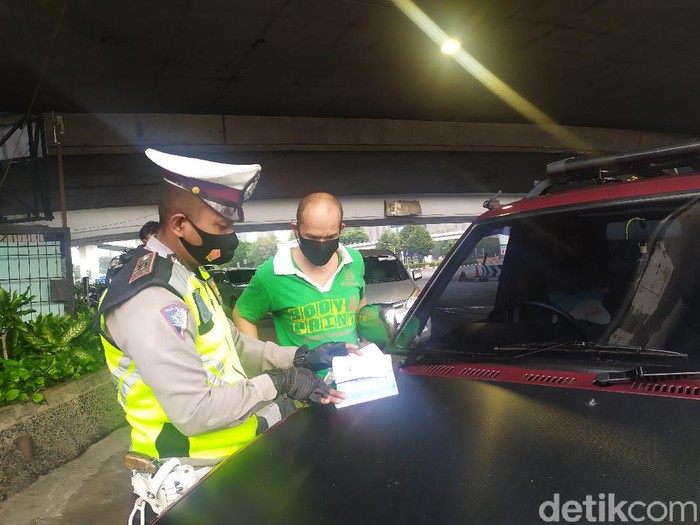 Polisi menilang pelanggar ganjil genap di Tomang, Jakarta.