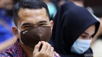 Meski tertutup masker, bos PS Store itu terlihat tersenyum saat menunggu sidang dimulai.