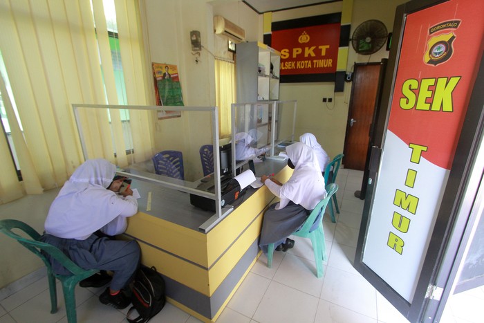 SISWA BELAJAR DARING DI POLSEK Seorang Bhabinkamtibmas mengawasi sejumlah siswa yang belajar di Polsek Kota Timur, Kota Gorontalo, Gorontalo, Selasa (18/8/2020). Polsek tersebut menyediakan jaringan internet gratis dan ruangan belajar bagi siswa yang tidak memiliki gawai cerdas maupun paket data internet untuk belajar daring sejak bulan Juli 2020 lalu. ANTARA FOTO/Adiwinata Solihin/foc.