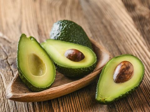Avocado on old wooden table in bowl. Halfs of avocados fresh fruits healthy food.