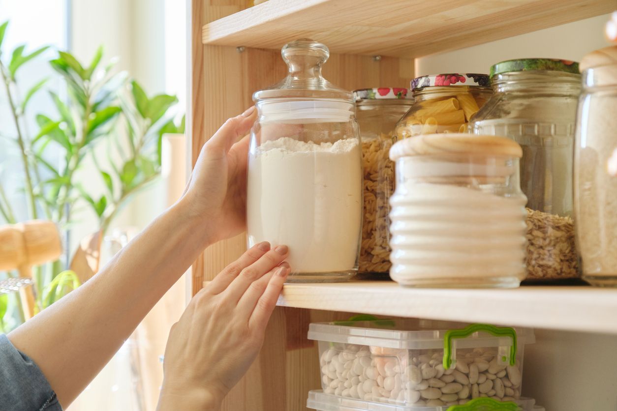 Food products in the kitchen storing ingredients in pantry. Woman taking jar of flour