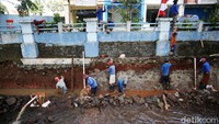 Pekerja membongkar dinding turap yang rusak. Setelah itu mereka membangun ulang dinding turap tersebut.